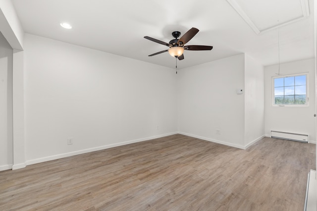 unfurnished room featuring a baseboard heating unit, baseboards, attic access, light wood-style floors, and a ceiling fan