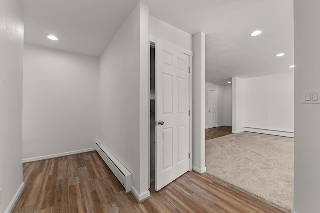 hallway with a baseboard heating unit, baseboards, baseboard heating, recessed lighting, and wood finished floors