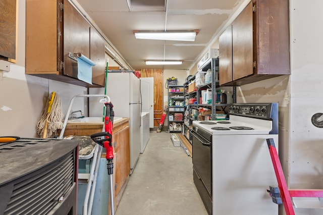 kitchen featuring electric range, concrete flooring, freestanding refrigerator, and a sink