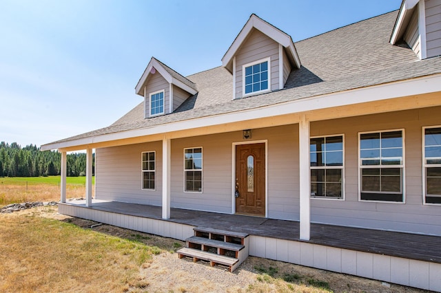 view of front facade featuring roof with shingles, a porch, and a front yard