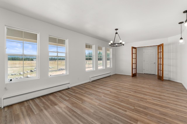 unfurnished dining area with light wood-style floors, baseboard heating, and a notable chandelier