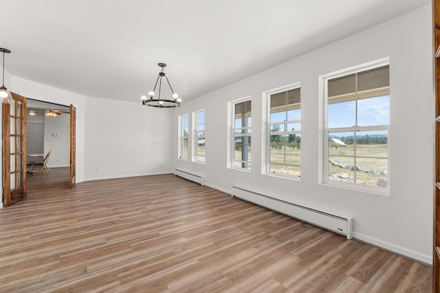 unfurnished dining area with light wood-type flooring, a baseboard heating unit, and a notable chandelier