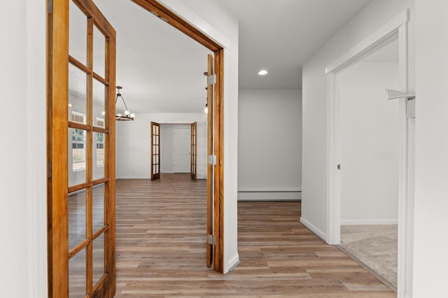 hallway featuring wood finished floors, recessed lighting, a baseboard radiator, baseboards, and a chandelier