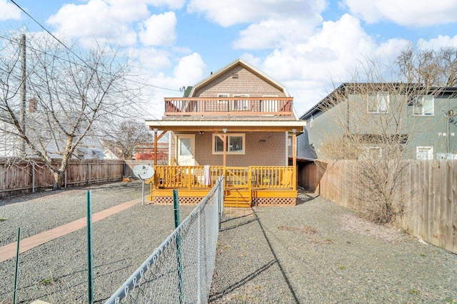 view of front of home with a fenced backyard, a gambrel roof, and a wooden deck