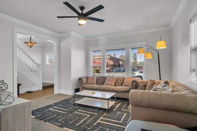 living area with stairway, baseboards, ceiling fan, ornamental molding, and carpet flooring