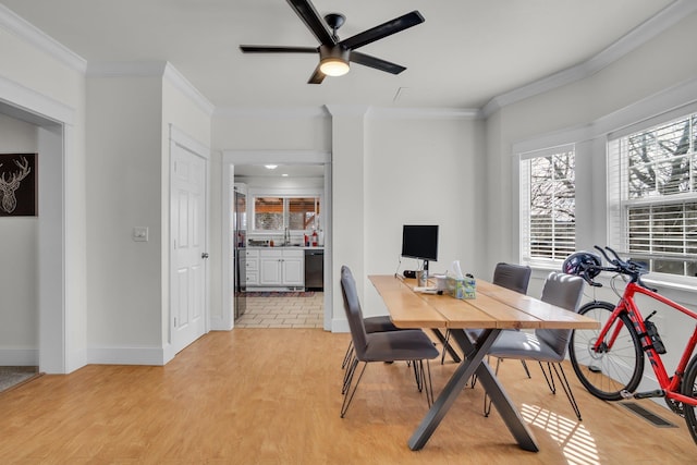 dining space featuring light wood-type flooring, crown molding, and baseboards