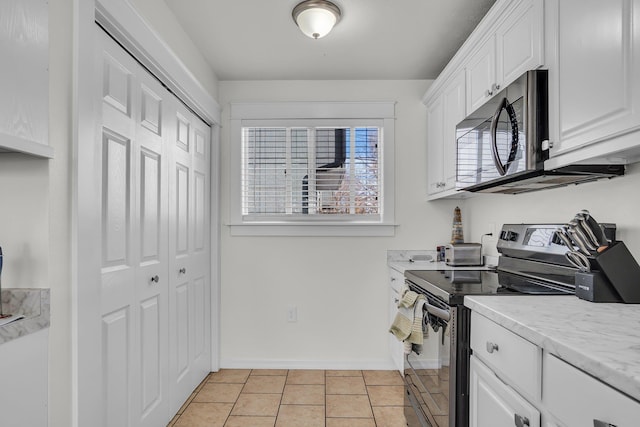 kitchen featuring light tile patterned floors, baseboards, light countertops, appliances with stainless steel finishes, and white cabinetry