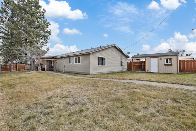 back of house with a lawn, an outdoor structure, a storage shed, and a fenced backyard