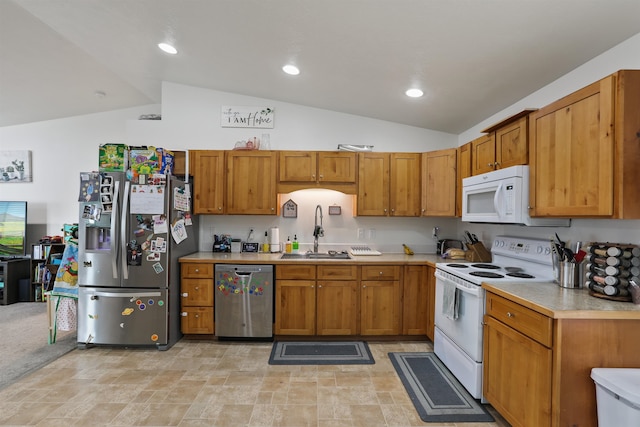 kitchen with a sink, stainless steel appliances, vaulted ceiling, and light countertops