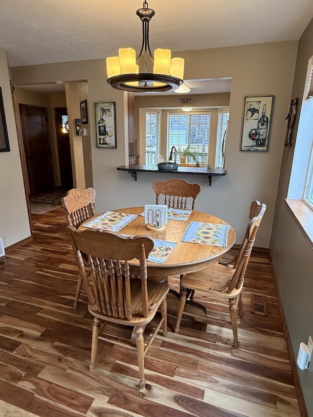 dining area featuring a notable chandelier, wood finished floors, visible vents, and baseboards