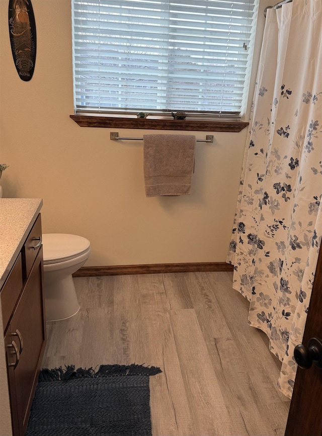 full bath with vanity, a shower with shower curtain, wood finished floors, baseboards, and toilet