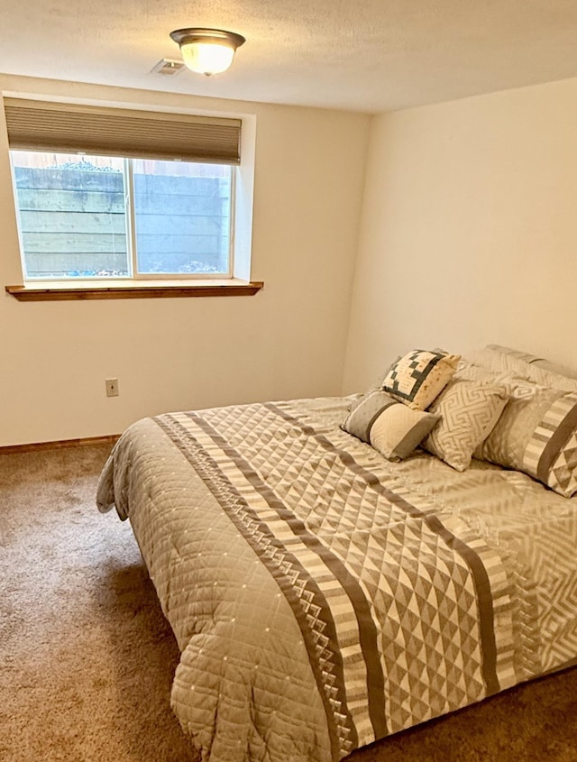 bedroom featuring visible vents, multiple windows, a textured ceiling, and carpet flooring