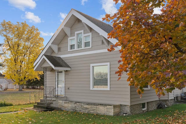 view of front of home featuring a shingled roof, a front yard, and fence