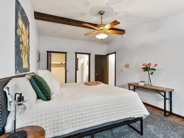 bedroom featuring vaulted ceiling with beams, baseboards, wood finished floors, a textured ceiling, and a ceiling fan