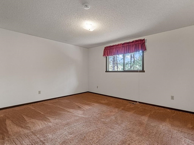 spare room with a textured ceiling, baseboards, and carpet