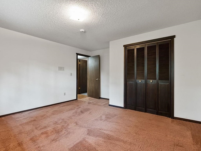 unfurnished bedroom with light carpet, a textured ceiling, baseboards, and a closet