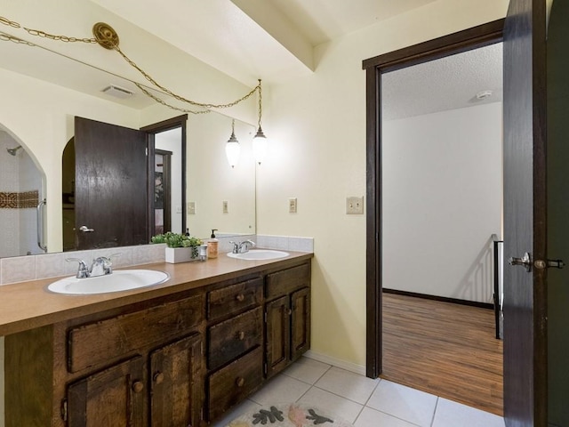 full bathroom with tile patterned floors, double vanity, baseboards, and a sink