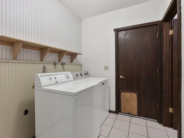 laundry room featuring a textured ceiling, laundry area, light tile patterned flooring, and washing machine and clothes dryer