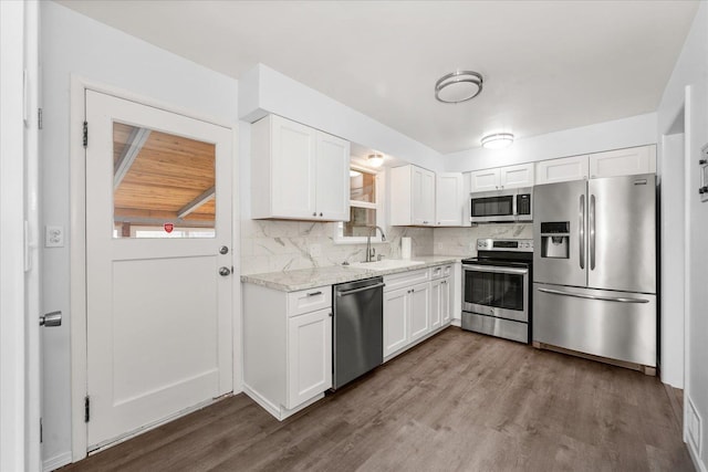 kitchen featuring a sink, tasteful backsplash, dark wood finished floors, stainless steel appliances, and white cabinets