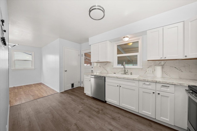 kitchen featuring a sink, stainless steel appliances, dark wood-type flooring, white cabinetry, and backsplash