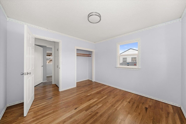 unfurnished bedroom with a closet, light wood-style floors, crown molding, and a textured ceiling