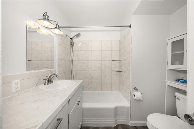 bathroom with baseboards, toilet, shower / bath combination, wood finished floors, and vanity