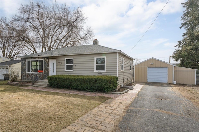 view of front of house featuring driveway, a chimney, an outdoor structure, a front lawn, and a detached garage