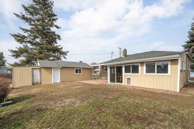 rear view of property featuring a yard and an outbuilding