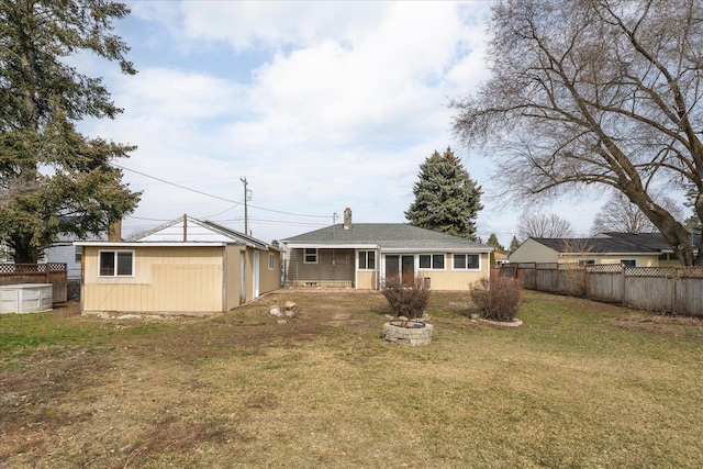 back of property with an outbuilding, a yard, and fence