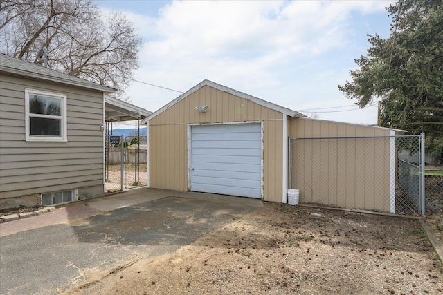 detached garage featuring aphalt driveway and fence