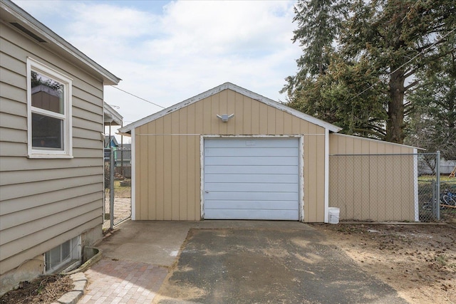 detached garage featuring driveway and fence