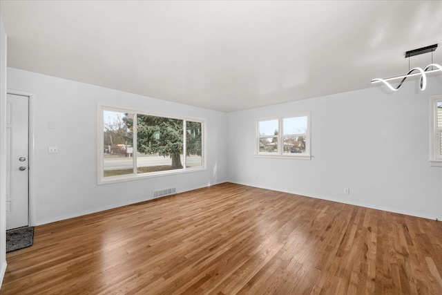 unfurnished room with visible vents, baseboards, and wood finished floors