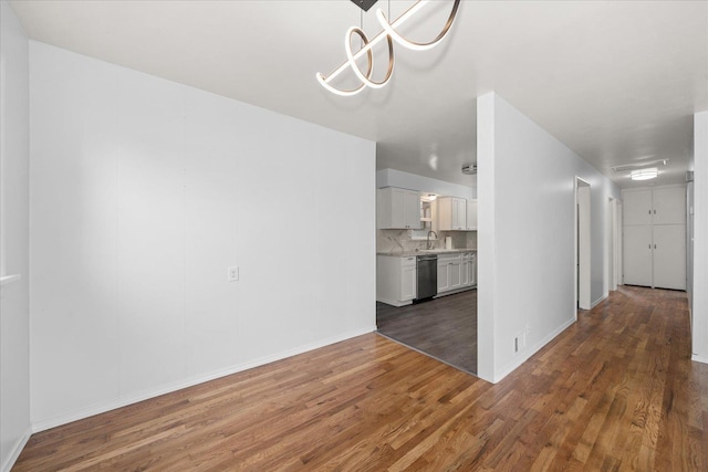 unfurnished dining area with wood finished floors, baseboards, and a sink