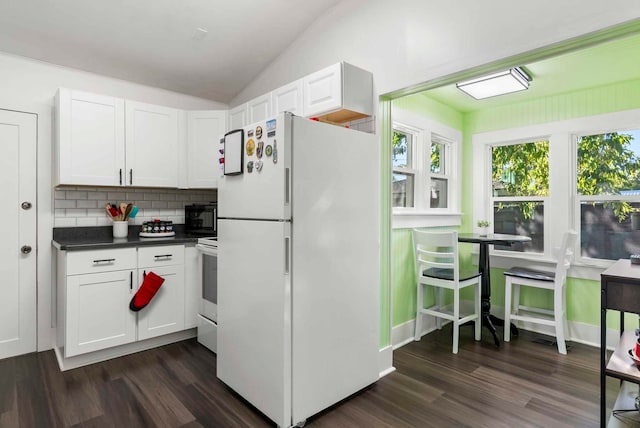 kitchen with lofted ceiling, white cabinets, freestanding refrigerator, and range with electric stovetop