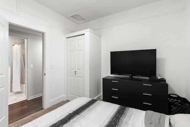 bedroom featuring visible vents, wood finished floors, a closet, baseboards, and attic access