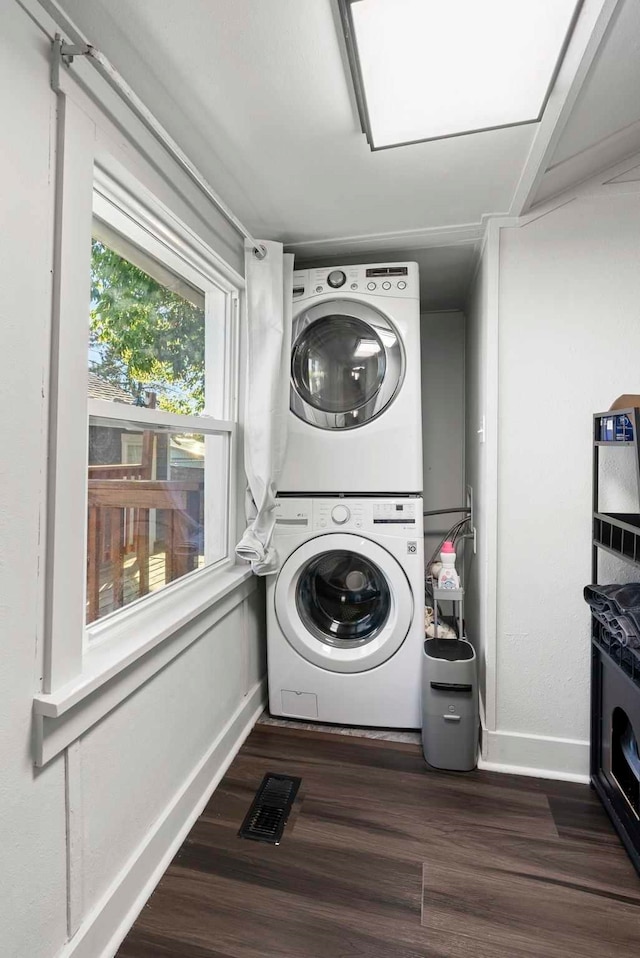 laundry area with visible vents, stacked washer and clothes dryer, dark wood-style floors, baseboards, and laundry area