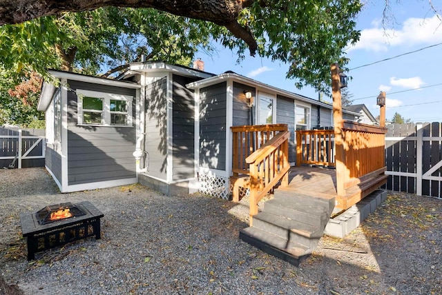 back of property featuring a wooden deck, fence, and a fire pit