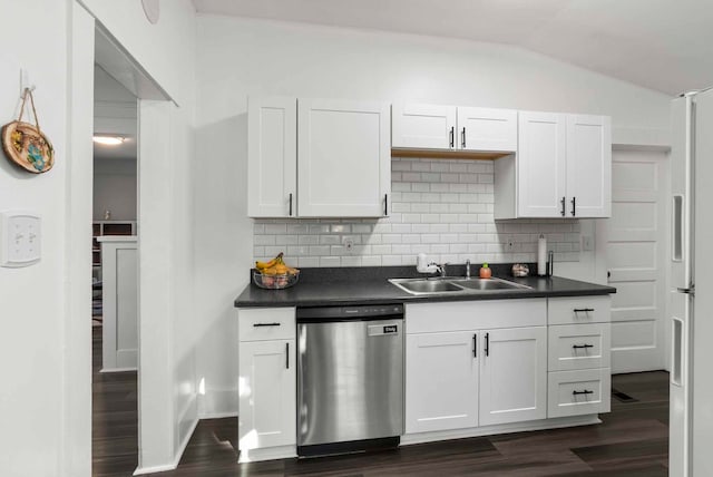 kitchen featuring lofted ceiling, freestanding refrigerator, a sink, stainless steel dishwasher, and dark countertops