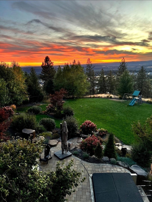 yard at dusk featuring a patio and a playground