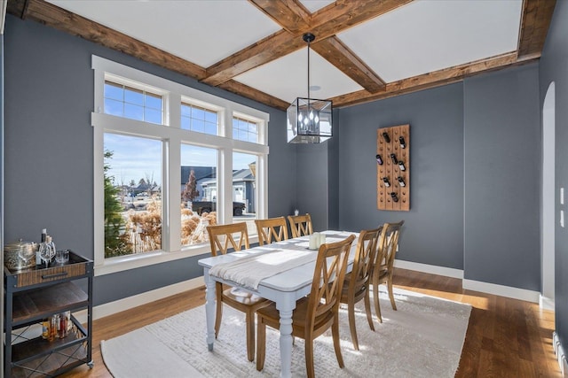 dining area with beam ceiling, baseboards, a healthy amount of sunlight, and wood finished floors