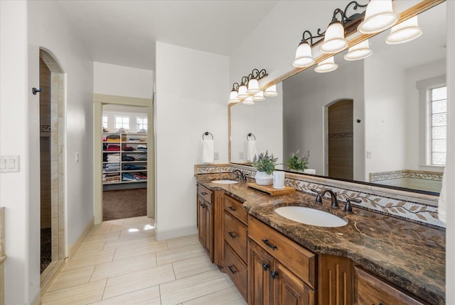 full bath with double vanity, a spacious closet, and a sink