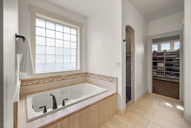 full bathroom with a walk in closet, a jetted tub, and a shower stall