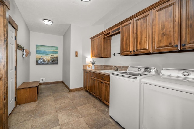 laundry area featuring washing machine and dryer, cabinet space, baseboards, and a sink