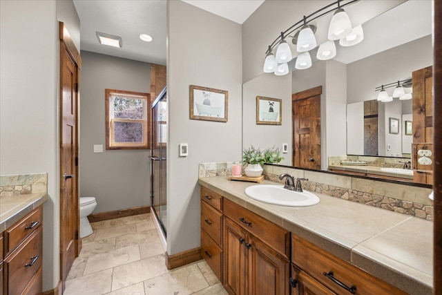 bathroom featuring baseboards, toilet, vanity, and a shower stall