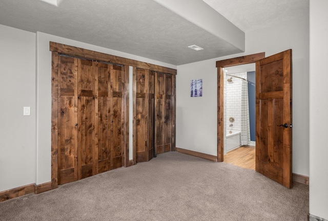 unfurnished bedroom with baseboards, a textured ceiling, and carpet flooring