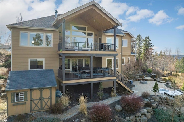 back of house featuring stairs, an outdoor structure, a balcony, and a storage unit