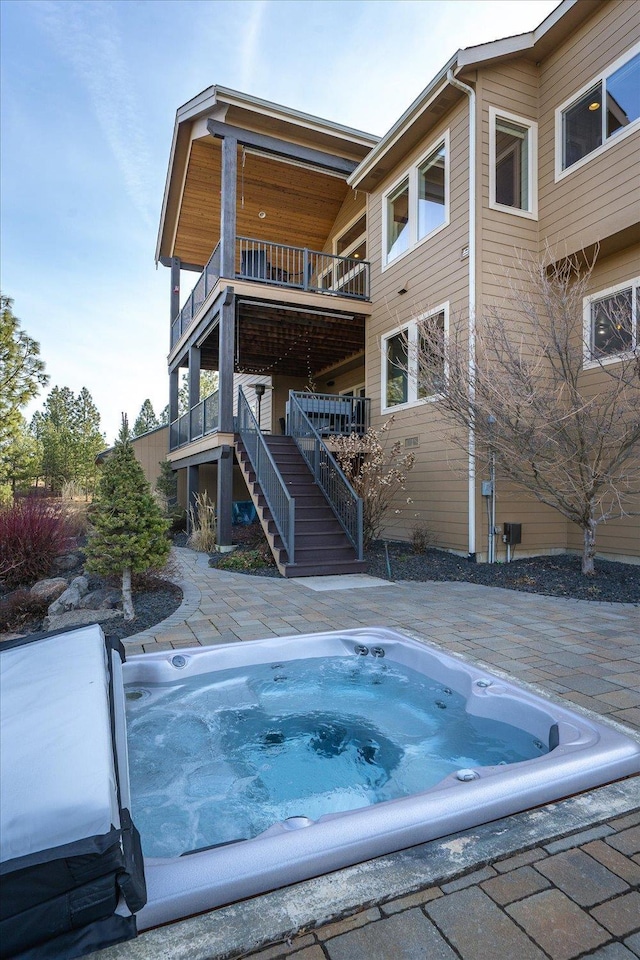 view of swimming pool featuring stairs and hot tub deck surround