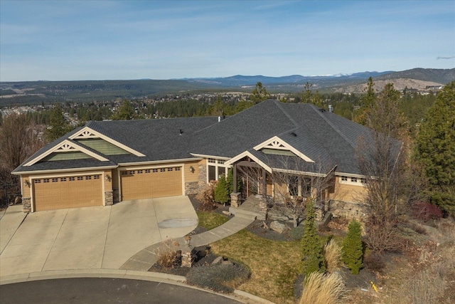 view of front of home with a mountain view, stone siding, driveway, and an attached garage