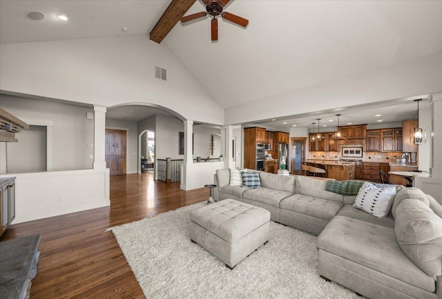 living room with visible vents, beam ceiling, dark wood-style floors, arched walkways, and decorative columns