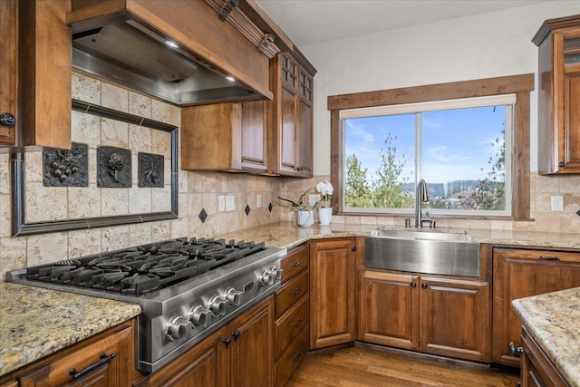 kitchen featuring custom exhaust hood, dark wood-style flooring, a sink, decorative backsplash, and stainless steel gas stovetop